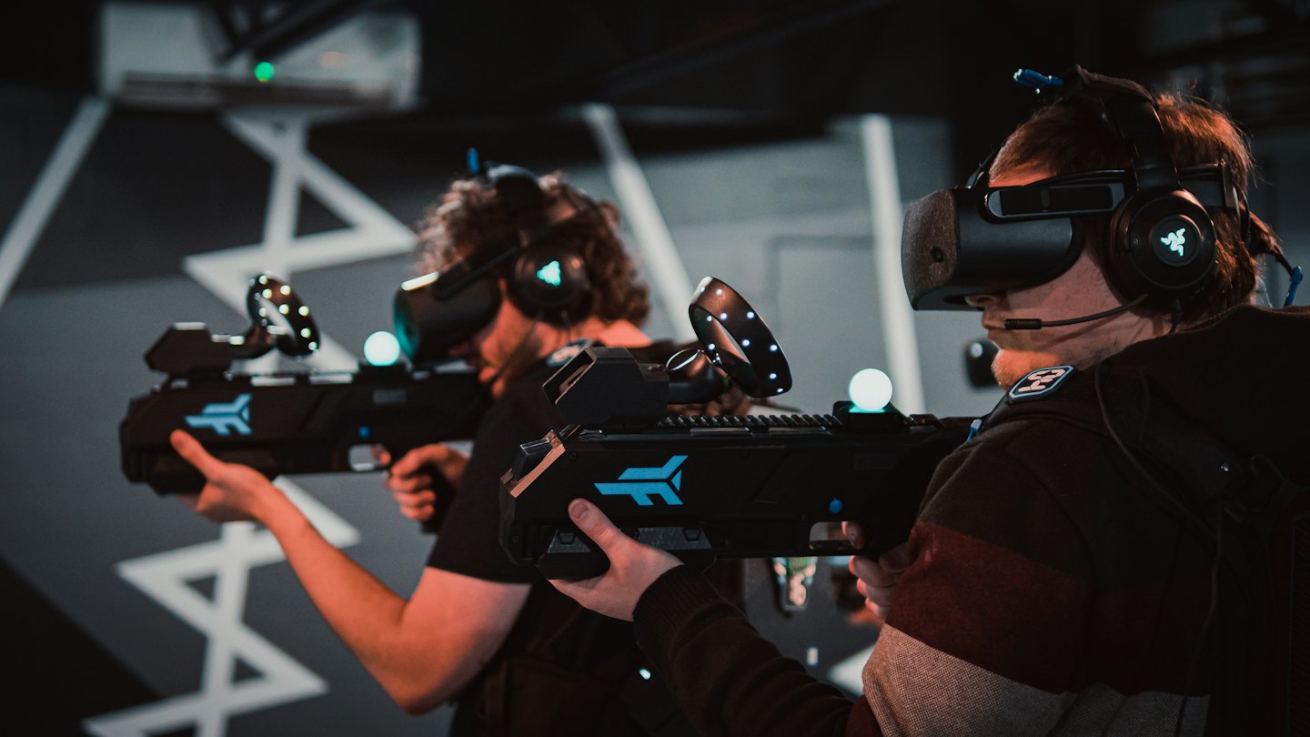 Twee mensen spelen een VR-game met futuristische controllers.